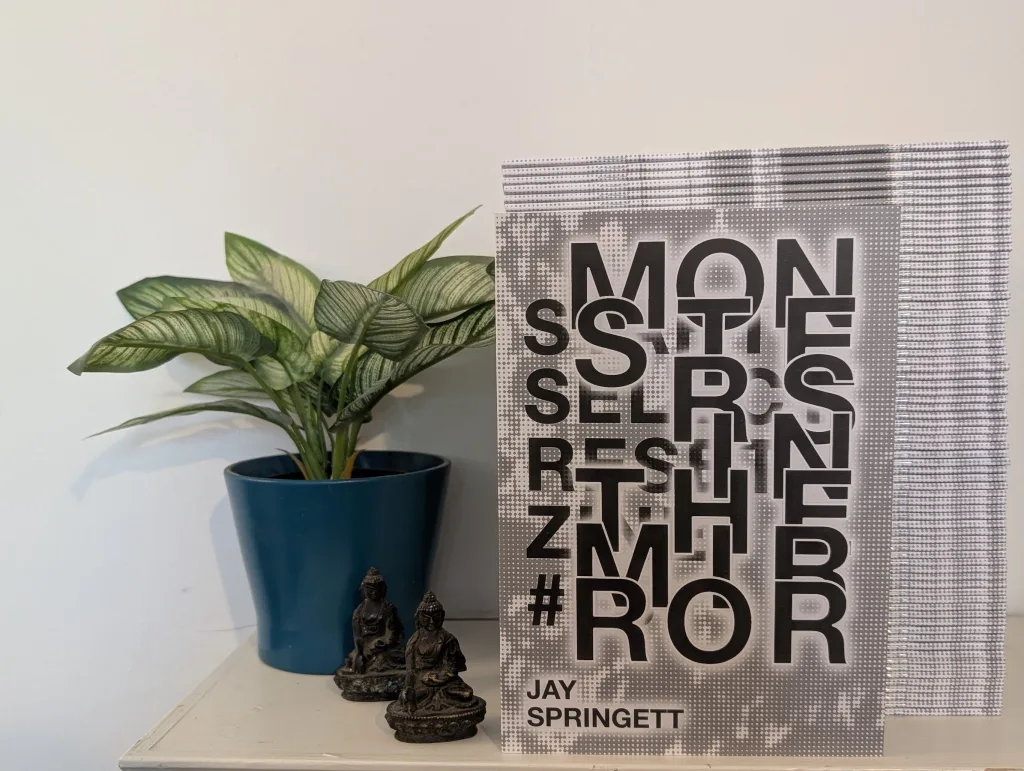 Start Select Reset Issue 15: Monsters in the Mirror — the zine propped up next to a potted plant and two small figurines.